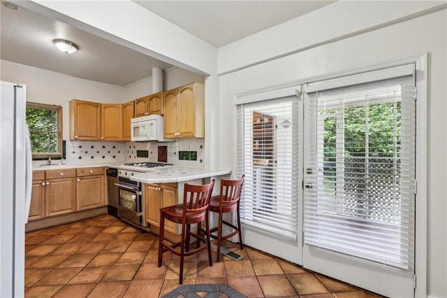 kitchen featuring white appliances, backsplash, a sink, and light tile patterned floors