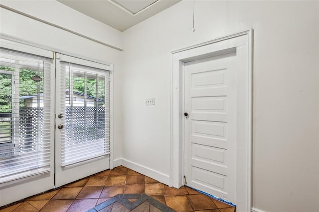 doorway to outside with baseboards and dark tile patterned flooring
