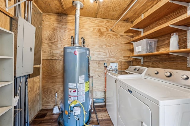 laundry area with gas water heater, dark wood finished floors, electric panel, separate washer and dryer, and wooden walls