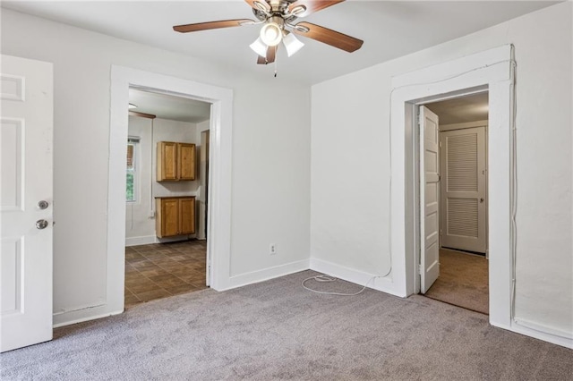 unfurnished bedroom with carpet flooring, baseboards, ensuite bath, and ceiling fan