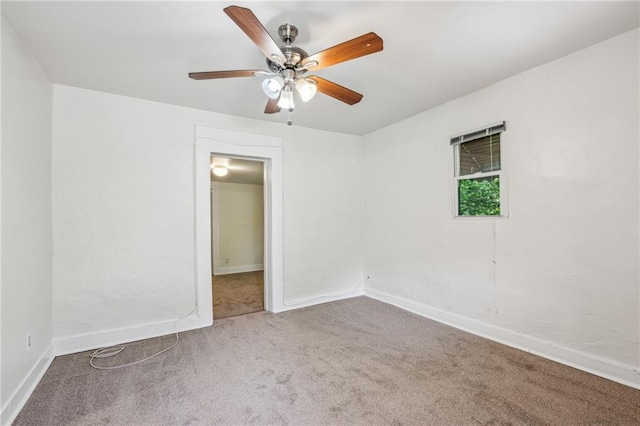 carpeted empty room with a ceiling fan and baseboards