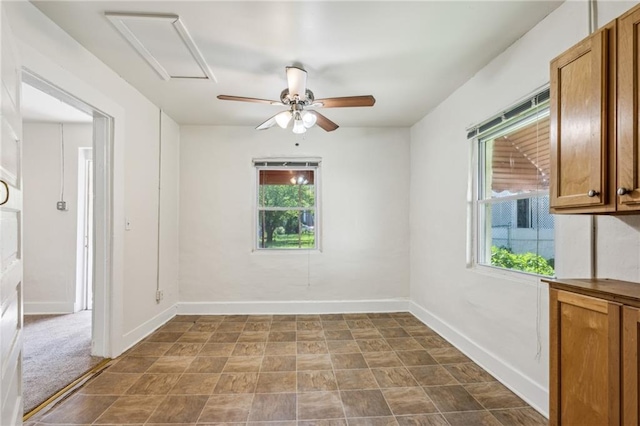 unfurnished room featuring ceiling fan, baseboards, and attic access
