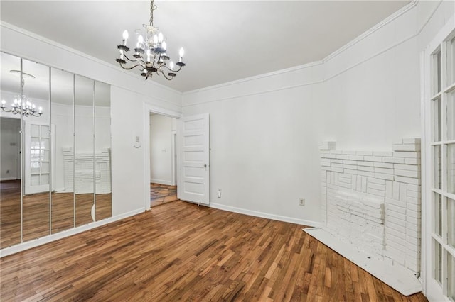 unfurnished bedroom featuring a chandelier, wood finished floors, ornamental molding, and baseboards