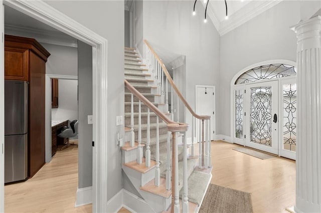 entryway with stairway, light wood-type flooring, ornamental molding, and baseboards