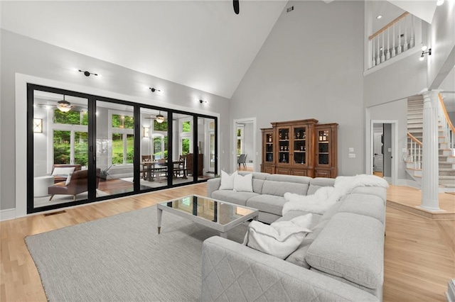 living area featuring a wealth of natural light, high vaulted ceiling, ceiling fan, and stairway