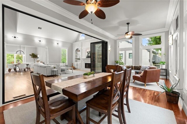 dining area featuring light wood-style floors, built in features, crown molding, a ceiling fan, and lofted ceiling