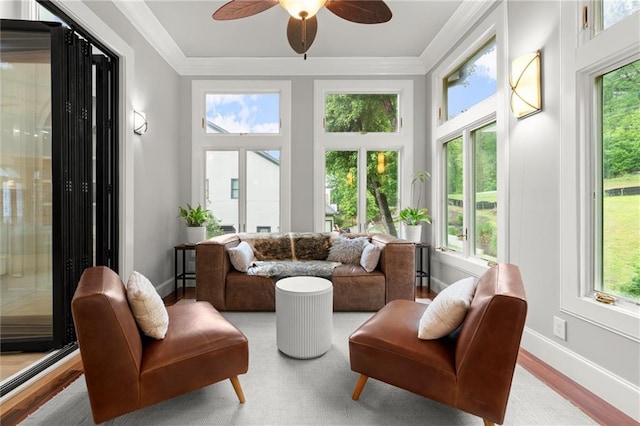 sunroom featuring crown molding, baseboards, wood finished floors, and plenty of natural light