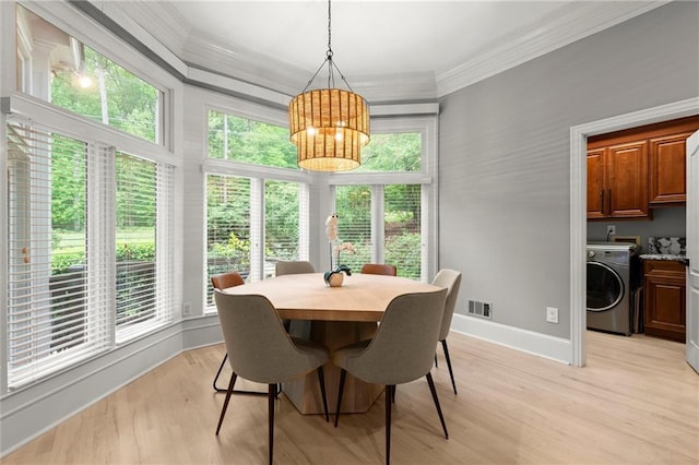 dining area featuring an inviting chandelier, light wood-style flooring, washer / dryer, ornamental molding, and visible vents
