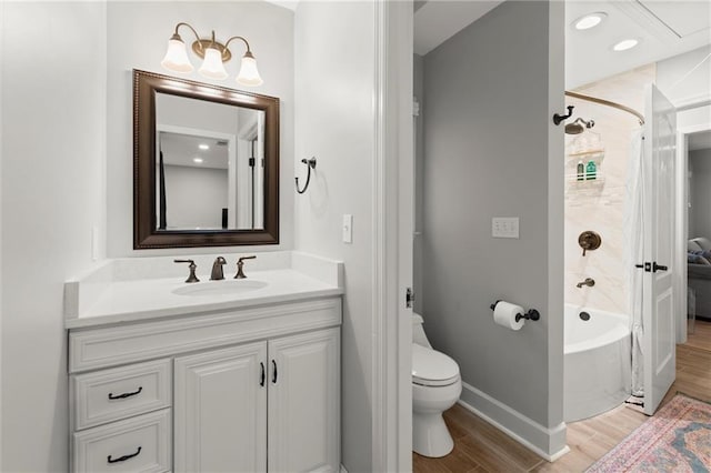 bathroom with baseboards, toilet, shower / bath combination, wood finished floors, and vanity