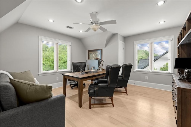 office area with lofted ceiling, visible vents, light wood-style floors, baseboards, and a ceiling fan