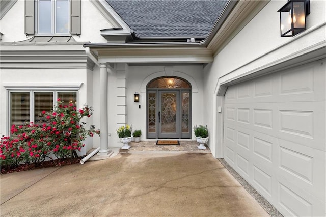 property entrance with a garage, a shingled roof, stucco siding, and driveway