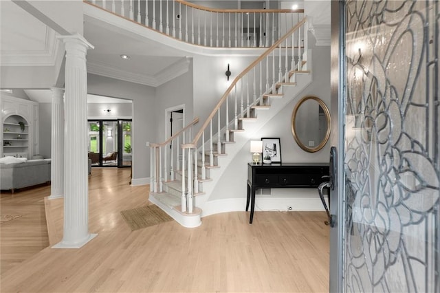 entrance foyer with ornate columns, a towering ceiling, ornamental molding, and stairs