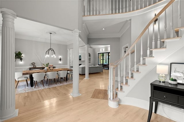 foyer featuring a high ceiling, stairway, wood finished floors, and ornate columns