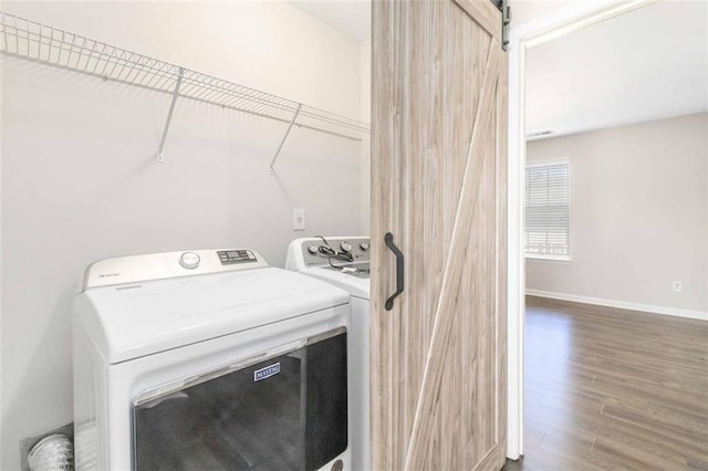 washroom with hardwood / wood-style floors, a barn door, and washing machine and clothes dryer