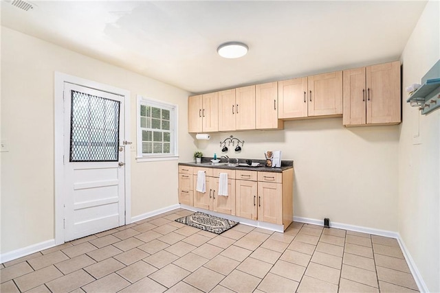 kitchen with light tile patterned flooring, sink, and light brown cabinetry