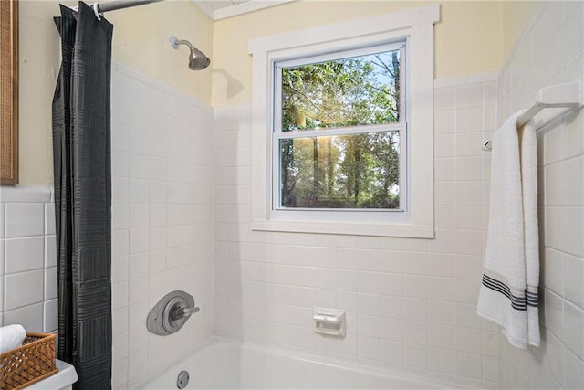 bathroom featuring a healthy amount of sunlight, shower / bath combo with shower curtain, and tile walls