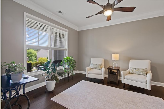 living area featuring crown molding, ceiling fan, baseboards, wood finished floors, and visible vents
