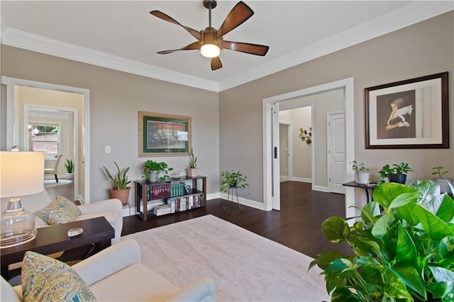living area featuring baseboards, ceiling fan, ornamental molding, and wood finished floors