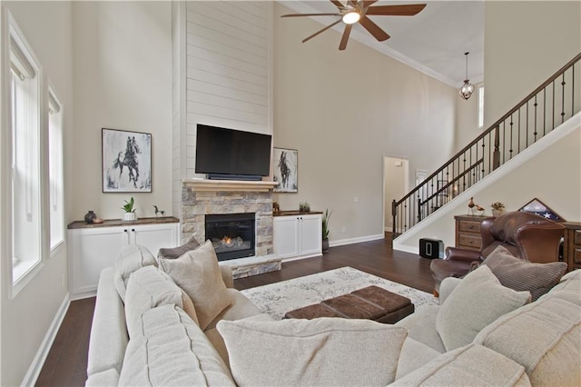 living room with dark wood-type flooring, stairs, ceiling fan, and a high ceiling