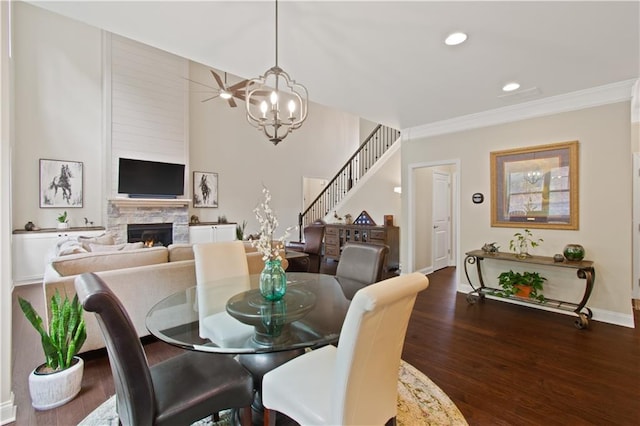 dining room with a stone fireplace, recessed lighting, wood finished floors, and a notable chandelier