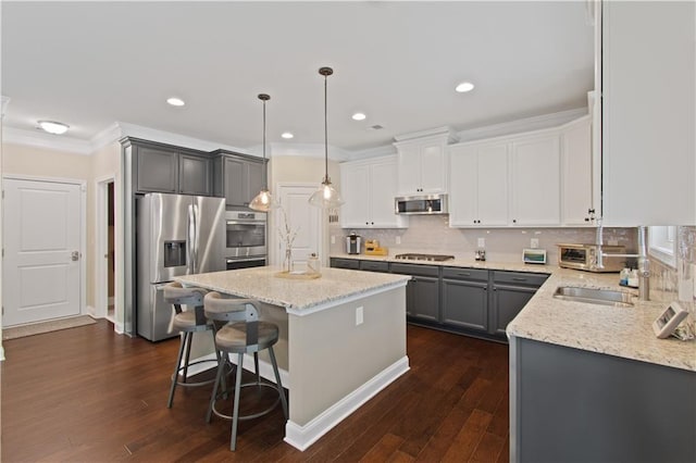 kitchen with light stone countertops, appliances with stainless steel finishes, dark wood-type flooring, a kitchen island, and ornamental molding