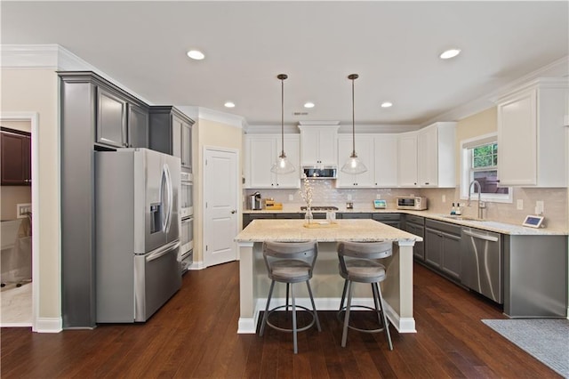 kitchen featuring a kitchen island, stainless steel appliances, a sink, and dark wood-style flooring