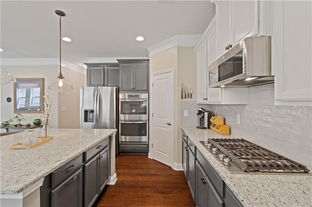 kitchen featuring ornamental molding, appliances with stainless steel finishes, dark wood-style floors, and light stone counters