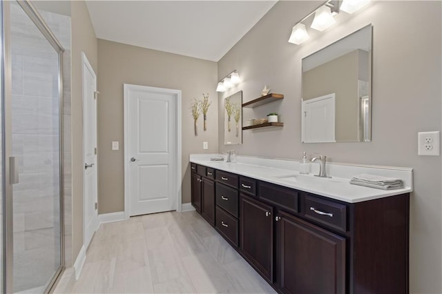 full bath with a sink, baseboards, a stall shower, and double vanity