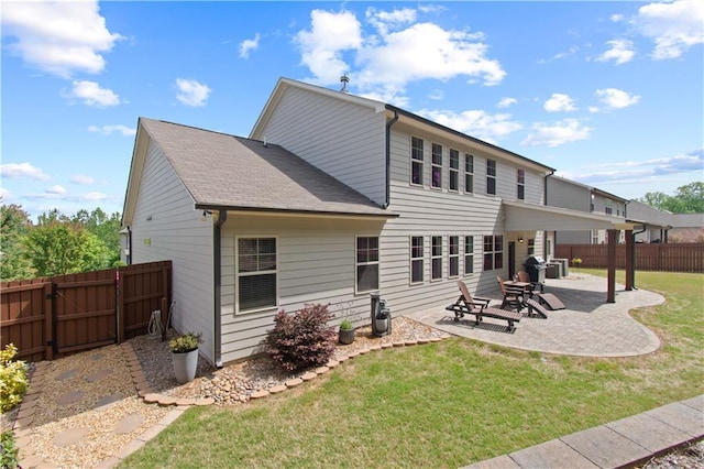 rear view of property featuring a lawn, a gate, a patio area, a fenced backyard, and a shingled roof