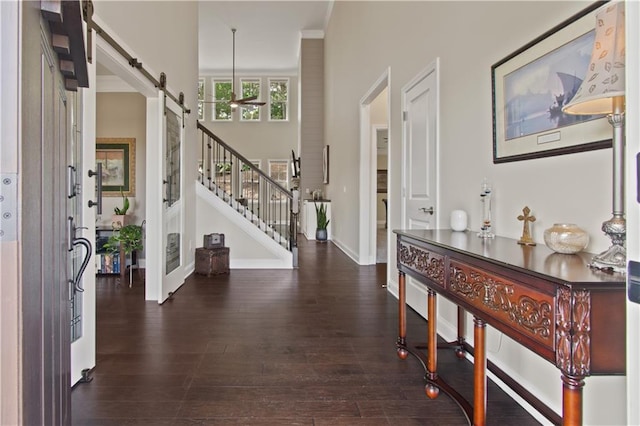 foyer entrance with baseboards, stairs, a barn door, and dark wood-type flooring