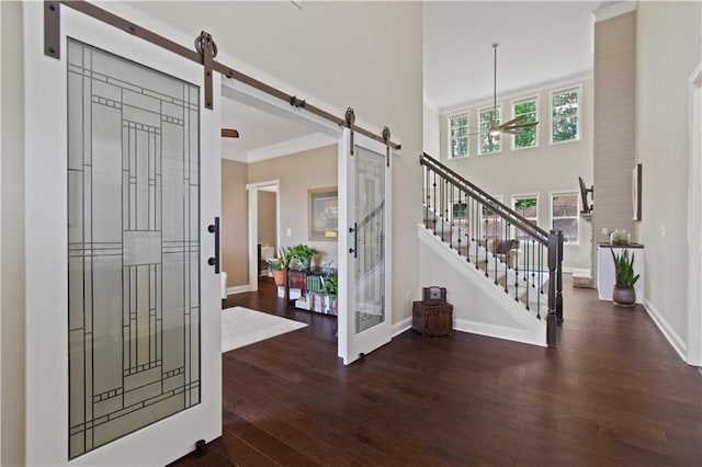 entryway featuring hardwood / wood-style floors, baseboards, ornamental molding, and a barn door