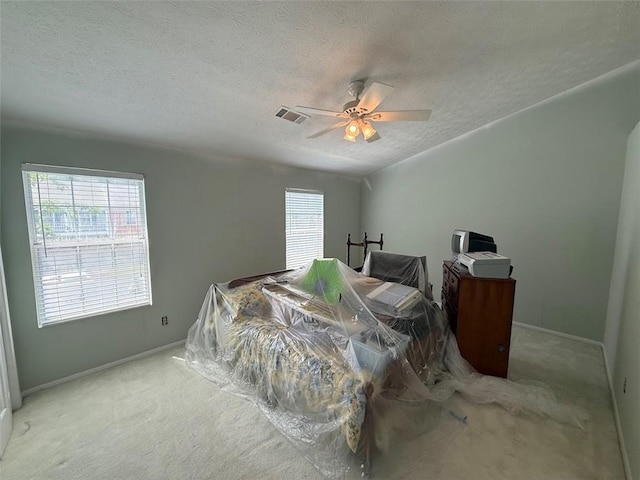 carpeted bedroom with visible vents, a textured ceiling, baseboards, and ceiling fan