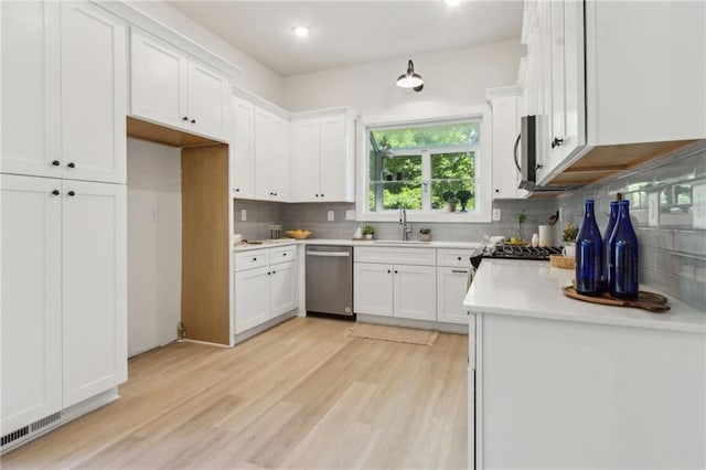 2010 Barnes Mill Rd, Marietta, GA 30062 - kitchen featuring appliances with stainless steel finishes, tasteful backsplash, white cabinetry, light wood-type flooring, and recessed lighting