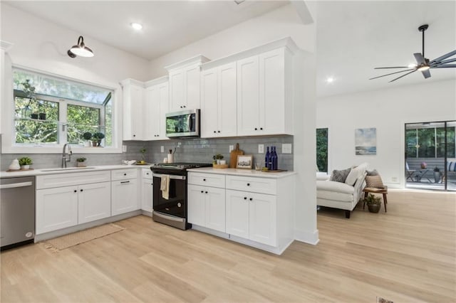 2010 Barnes Mill Rd, Marietta, GA 30062 - kitchen with appliances with stainless steel finishes, open floor plan, backsplash, light wood-style floors, and light countertops