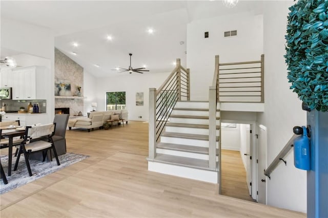 2010 Barnes Mill Rd, Marietta, GA 30062 - dining space with stairway, light wood finished floors, a large fireplace, a ceiling fan, and high vaulted ceiling