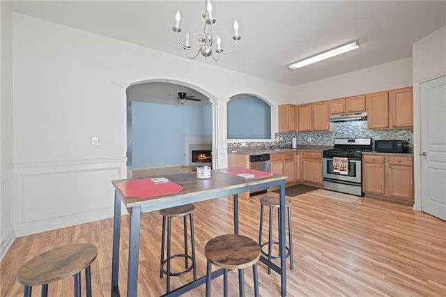 kitchen with tasteful backsplash, hanging light fixtures, light wood-type flooring, and appliances with stainless steel finishes