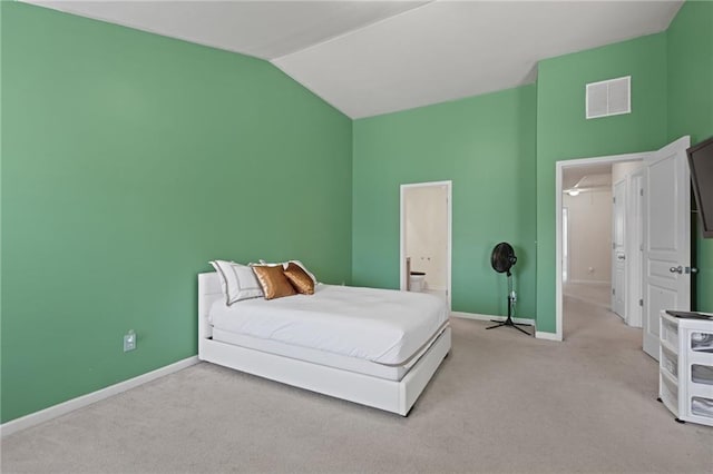 bedroom featuring vaulted ceiling, connected bathroom, and light carpet