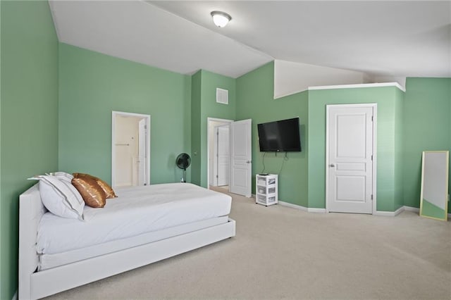 bedroom with lofted ceiling, connected bathroom, and carpet floors