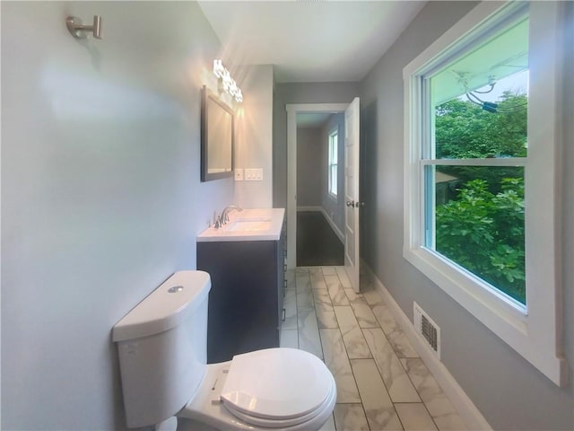 bathroom with vanity, toilet, and a wealth of natural light