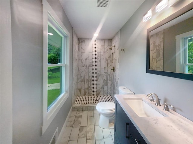 bathroom with toilet, vanity, and tiled shower