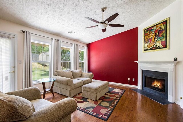 7057 Silver Bend Ovrlk, Austell, GA 30168 - living room with a textured ceiling, ceiling fan, a lit fireplace, vaulted ceiling, and wood finished floors