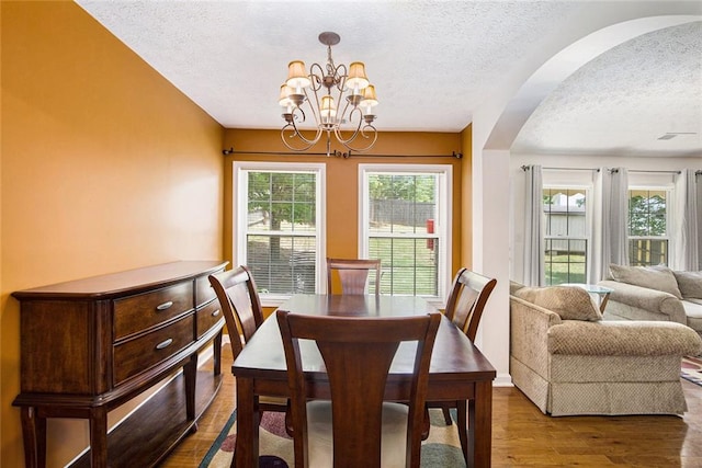 7057 Silver Bend Ovrlk, Austell, GA 30168 - dining room featuring a textured ceiling, a chandelier, arched walkways, and dark wood finished floors