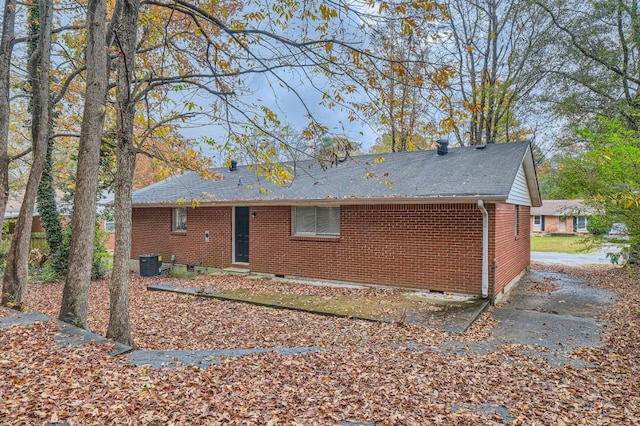 back of house with crawl space, roof with shingles, central AC unit, and brick siding