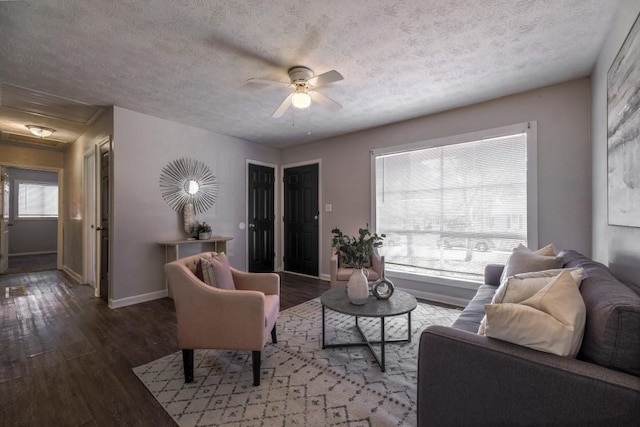 living area featuring a ceiling fan, a textured ceiling, baseboards, and wood finished floors