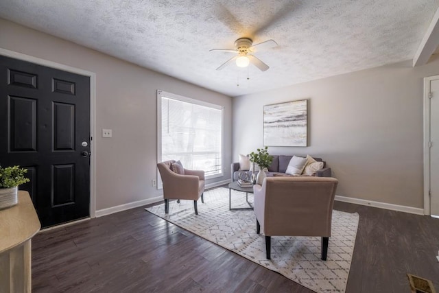 living area featuring ceiling fan, a textured ceiling, baseboards, and wood finished floors