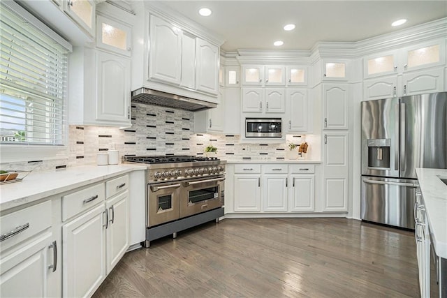 kitchen with stainless steel appliances, white cabinets, tasteful backsplash, glass insert cabinets, and wood finished floors