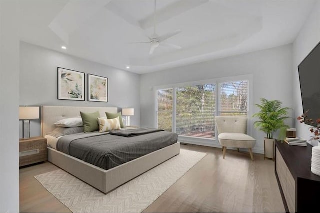 bedroom with a tray ceiling, recessed lighting, wood finished floors, and ceiling fan