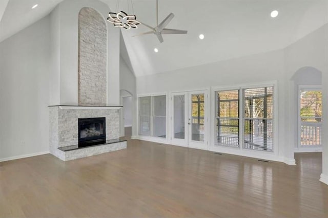 unfurnished living room featuring baseboards, a fireplace, wood finished floors, high vaulted ceiling, and a ceiling fan