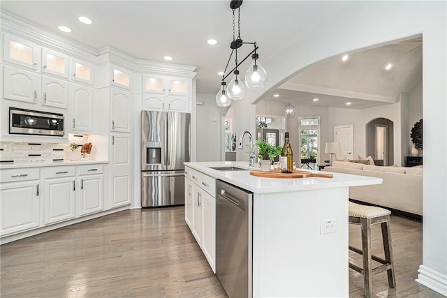 kitchen featuring stainless steel appliances, arched walkways, a sink, white cabinetry, and a kitchen breakfast bar