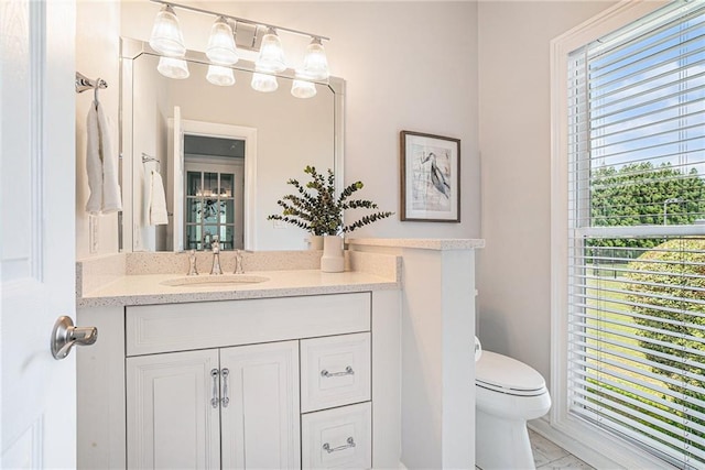 half bathroom featuring plenty of natural light, toilet, and vanity